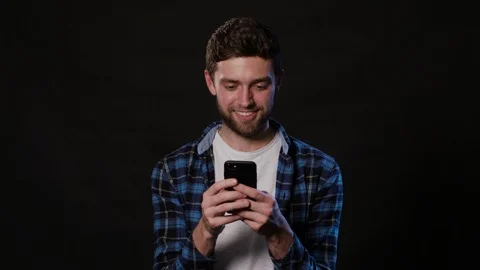 A Man Using a Phone Against a Black Background Stock Footage 88387086