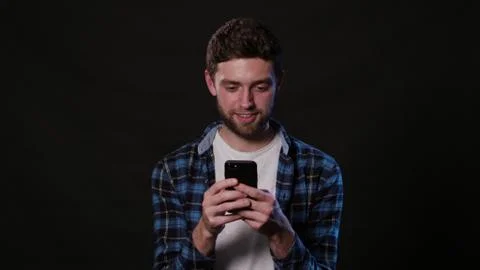 A Man Using a Phone Against a Black Background Stock Photos