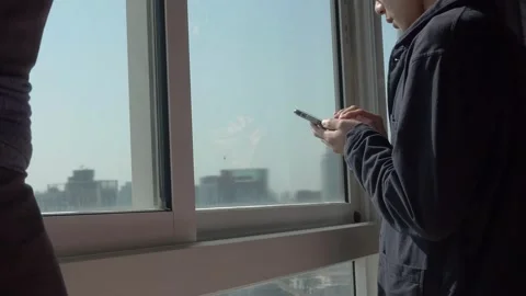 Man using phone and standing by the window Stock Footage 127237637