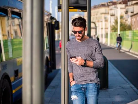 Man using phone at bus stop Stock Photos