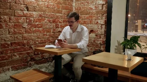 Man using phone at cafe table with notebook Stock Footage 342779625