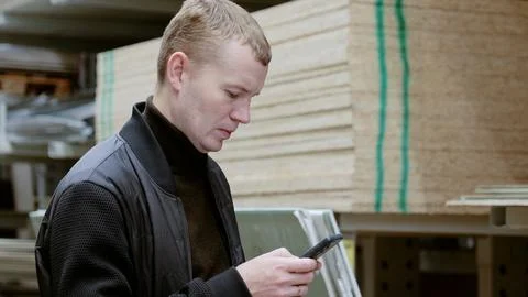 Man using phone to choose construction materials in hardware store for diy Stock Photos