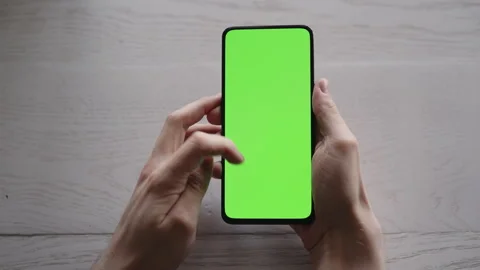 Man using phone with green screen on white oak table Stock Footage 347998407
