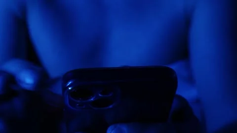 Man using phone late at night in dark room with TV light. Stock Footage 243372145