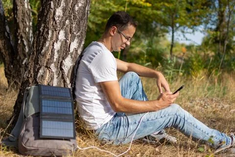 Man using phone in nature, surrounded by trees and grass, showing joy Stock Photos