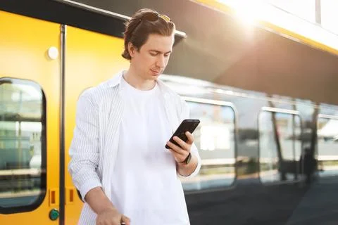 Man using a phone while waiting on a platform for a train. Urban travel, co.. 库存照片