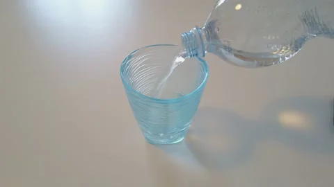 Man Using Plastic Bottle to Fills Blue Glass with Water Stock Footage 131396619