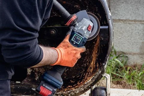 Man using portable grinder with sparkles 스톡 사진