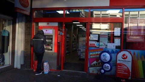 A man using the Post Office cash machine, cash point, ATM on the high Stock Footage 122947075