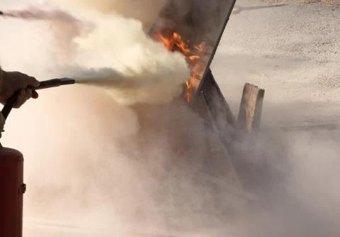 Man using powder type fire extinguisher fighting fire close up photo Stock Photos