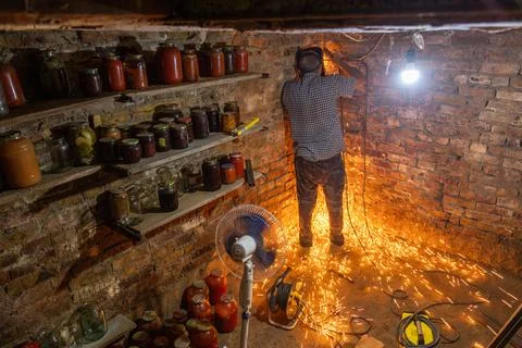 Man using power tool in dimly lit basement with sparks flying Stock Photos