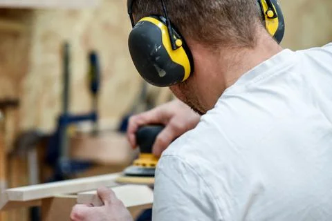 A man using a power tool electric sander to craft wood in the carpentry trade Stock Photos