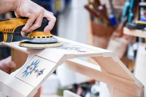 A man using a power tool electric sander to craft wood in the carpentry trade Stock Photos