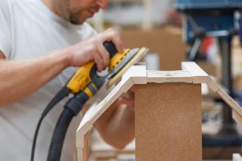 A man using a power tool electric sander to craft wood in the carpentry trade Stock Photos