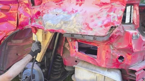 Man using a power tool on a wrecked Dodge Charger to bend metal out Stock Footage 149277480