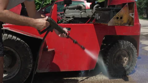 Man using pressure washer to clean red forklift Stock Footage 338309089