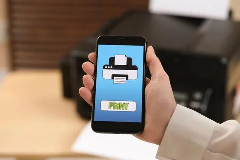 Man using printer management application on mobile phone indoors, closeup. .. Stock Photos