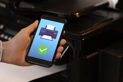 Man using printer management application on mobile phone indoors, closeup a.. Stock Photos