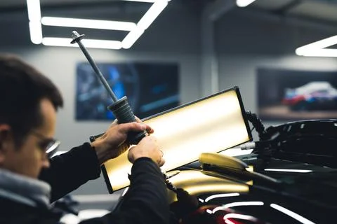 Man using professional tool and lamp to remove small dent from the back of a Stock Photos