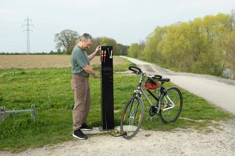 Man using a public bike pump station to inflate a tire. Stock Photos