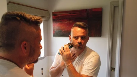 Man using a razor to put some finishing touches in on his beard, morning Stock Footage 121870054