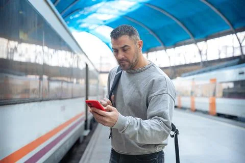 Man Using Red Smartphone at Train Station Stock Photos