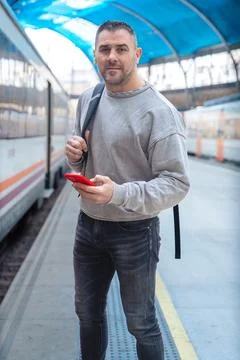 Man Using Red Smartphone at Train Station.Vertical Stock Photos