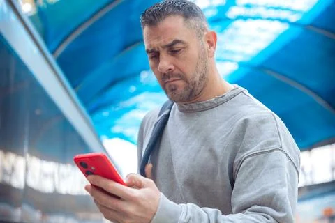 Man Using Red Smartphone at Train Station Stock Photos