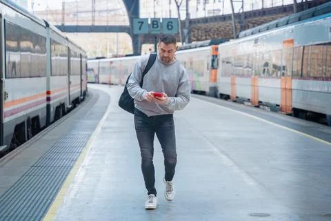 Man Using Red Smartphone at Train Station Stock Photos