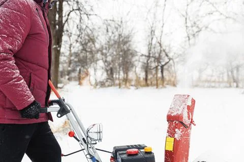 Man using red snowblower machine outdoor. Removing snow near house from yard Stock Photos