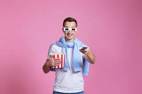 Man using remote and holding a big bucket of popcorns Stock Photos