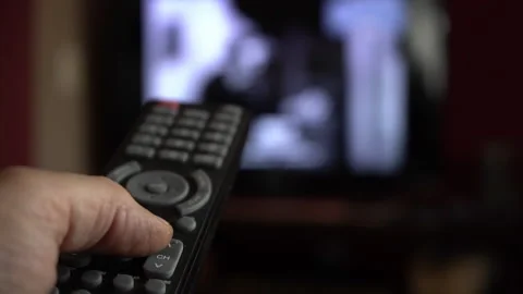 A man using a remote to channel surf on TV Stock Footage 194513476