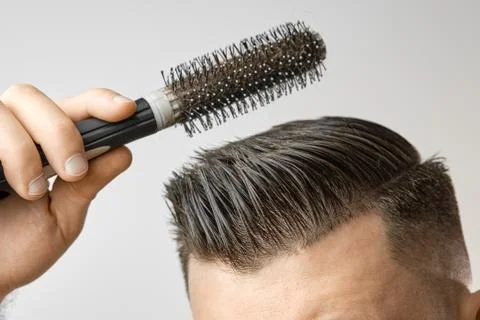 Man using a round brush for styling his hair. Hair care at home after barbershop Stock Photos
