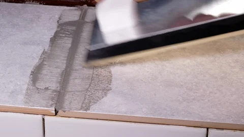 Man using a rubber float to apply grout to tiles. 스톡 동영상 100108247