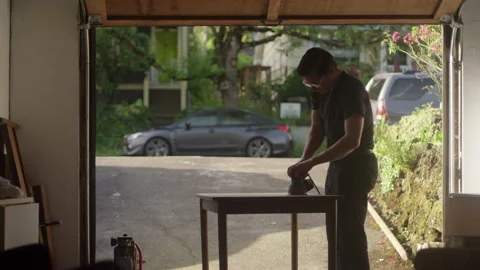 Man using a sander while restoring a wooden table in a garage 스톡 동영상 134288410