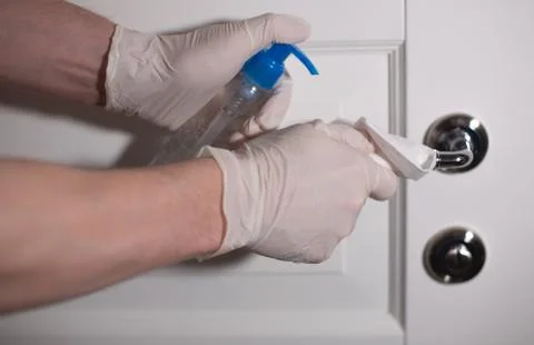Man using sanitizing gel to clean door handle Stock Photos