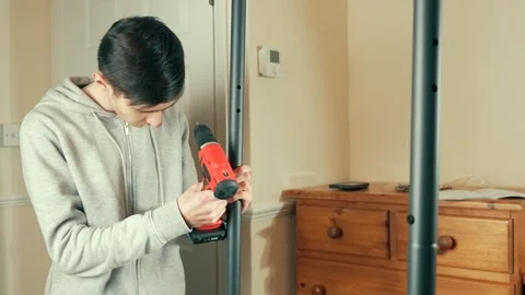 Man using screwdriver to assemble coat rack frame. Male fastening metal tube for Stock Footage 311988445