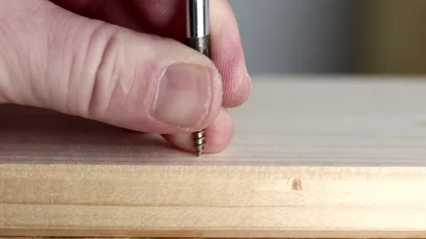 Man is using a screwdriver to drive a screw into a wooden board. Stock-Footage 344124629