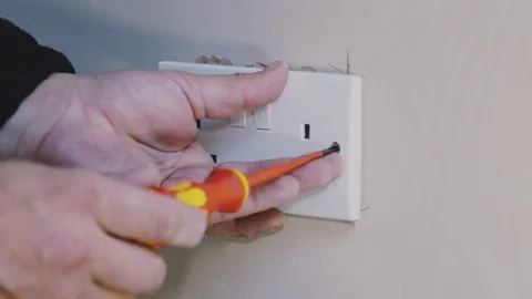Man using screwdriver to tighten an electrical socket Stock Footage 77680278