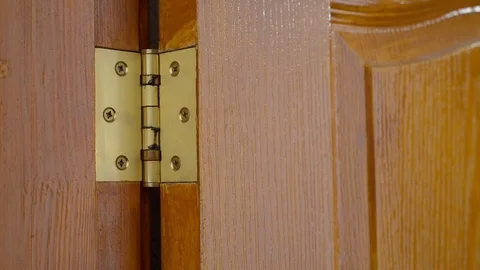 A man is using a screwdriver to unscrew a Door hinge Stock Footage 83576578