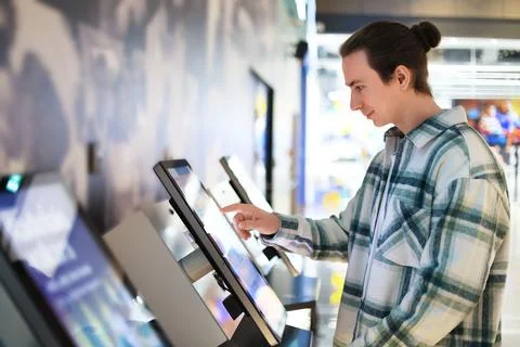 Man using self-service kiosk with touchscreen. Guy selecting options on int.. Stock Photos