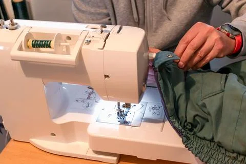 Man using a sewing machine with a garment, for repair work, customization, .. Stockfoto's