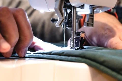 Man using a sewing machine with a garment, for repair work, customization, .. 库存照片