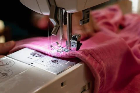 Man using a sewing machine with a pink garment, for repair work, customizat.. 스톡 사진