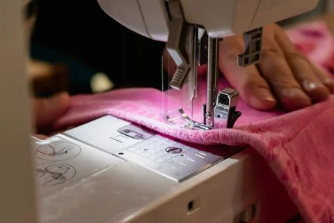 Man using a sewing machine with a pink garment, for repair work, customizat.. Stockfoto's