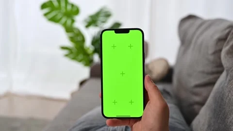Man using smarphone with green screen lying on the couch at home. Modern Stock Footage 249108673