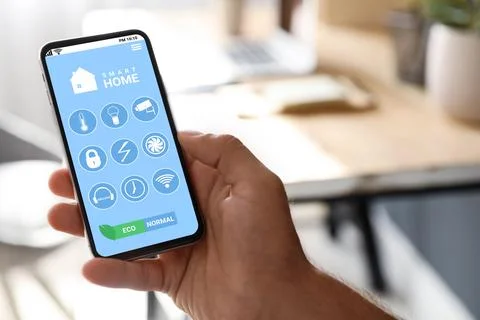 Man using Smart Home app on mobile phone indoors, closeup Stock Photos