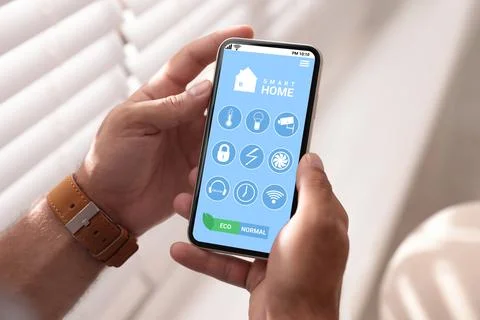 Man using Smart Home app on mobile phone indoors, closeup Stock Photos