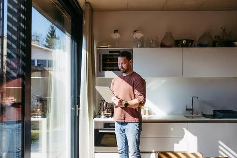 Man using smart home app to control electric window shades indoors. Stock Photos