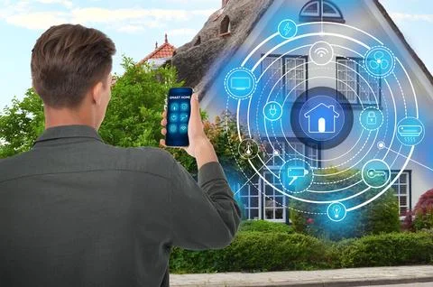 Man using smart home control system via application on mobile phone outdoor.. Stock Photos